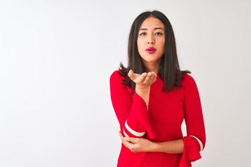Young beautiful chinese woman wearing red dress standing over isolated white background looking at the camera blowing a kiss with hand on air being lovely and sexy. Love expression.