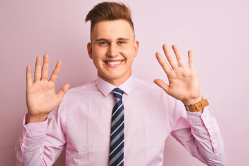 Young handsome businessman wearing shirt and tie standing over isolated pink background showing and pointing up with fingers number ten while smiling confident and happy.