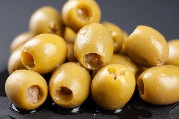 several olives lie on a black board on a black background macro super macro