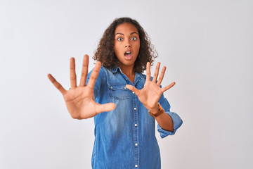 Young brazilian woman wearing denim shirt standing over isolated white background afraid and...
