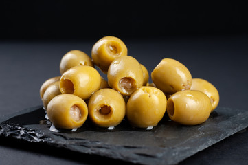 several olives lie on a black board on a black background macro super macro