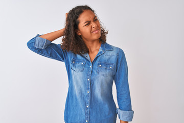 Young brazilian woman wearing denim shirt standing over isolated white background confuse and...