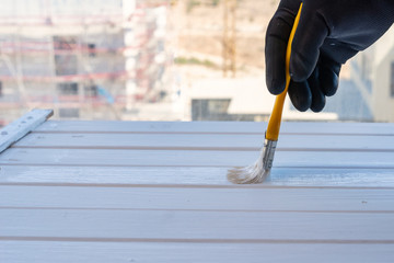 Painter holding brush on white wood surface.