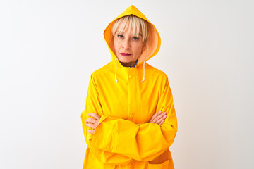 Middle age woman wearing rain coat with hood standing over isolated white background skeptic and nervous, disapproving expression on face with crossed arms. Negative person.