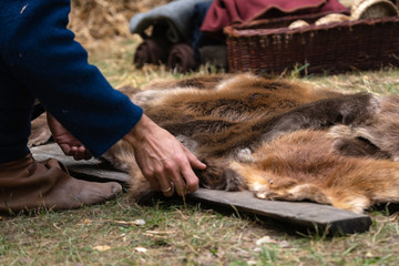Man hands picking up wild animal fur of the ground. Animal coat skin for sale at rural village