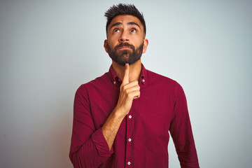 Young indian man wearing red elegant shirt standing over isolated grey background Thinking...