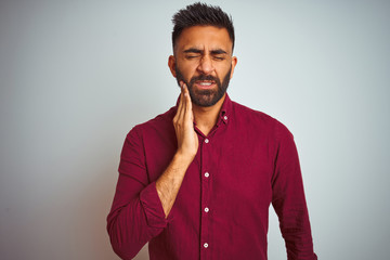 Fototapeta premium Young indian man wearing red elegant shirt standing over isolated grey background touching mouth with hand with painful expression because of toothache or dental illness on teeth. Dentist concept.