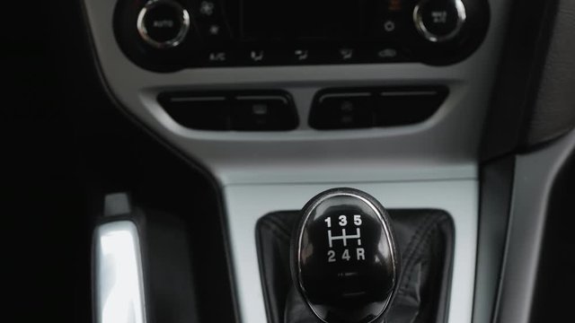Driver man controls auto and switch gears, then shifts to neutral gear and pulls the handbrake handle, close-up shot