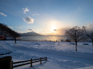 scenic view in winter at sunset time with view of trees without leaves at Lake Shikotsu, Chitose, Hokkaido, Japan
