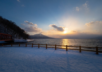 scenic view at Yamasentetsu Bridge in winter at sunset time with view of trees without leaves at Lake Shikotsu, Chitose, Hokkaido, Japan