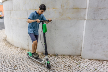 Lisbon, Portugal- july 4 2019: young boy riding electric scooter in the city.