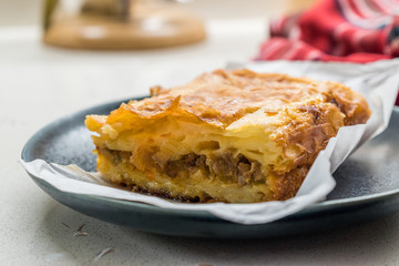 Turkish Borek with Minced Meat and Leek on Wooden Board with Paper.