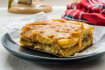 Turkish Borek with Minced Meat and Leek on Wooden Board with Paper.