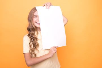 funny girl holding clear sheet of paper on orange background. mock up