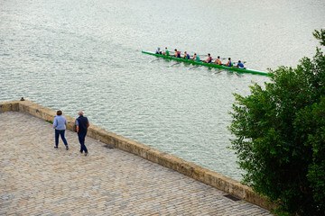 Seville, Spain - November 5, 2019: Pedestrians observe canoeists in the Alfonso XIII Canal in Seville.