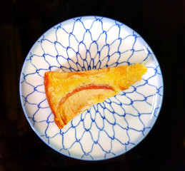 A piece of apple cake in plate on black background.