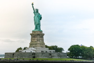 Fototapeta premium Photo close-up of the Statue of Liberty on a sunny day and blue sky with clouds. Liberty Island. NYC, USA