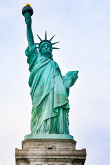 Fototapeta premium Zdjęcie z bliska Statua Wolności w słoneczny dzień i błękitne niebo z chmurami. Wyspa Wolności. NYC, USA