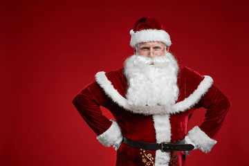 Portrait of happy Santa Claus in red costume and with white beard smiling at camera over red background