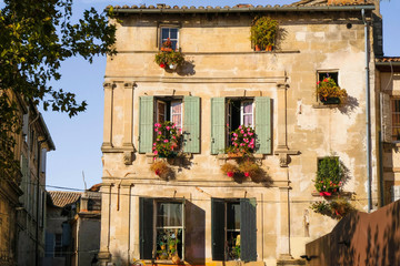 Picturesque old house with flowers in the windows in the city of Arles in Provence in the fall....