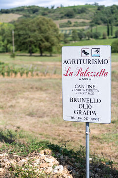 Montalcino, Italy - August 26, 2018: Val D'Orcia countryside in Tuscany with brown soil farm landscape winery vineyard with sign for agriturismo brunello wine