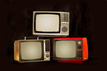 Three old retro television pile on a black background, old TV still life 