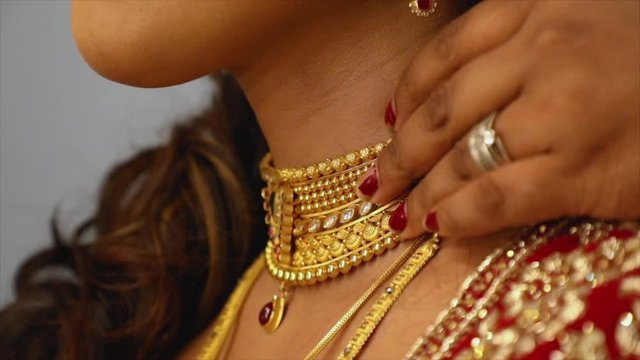 Gold necklace adjusted to fit on a beautiful neck of a gorgeous Indian bride, slow motion shot, wedding in India.