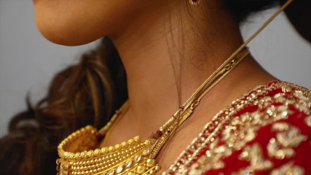 Gold necklace dragged across a beautiful neck of a gorgeous Indian bride, slow motion shot, wedding in India.