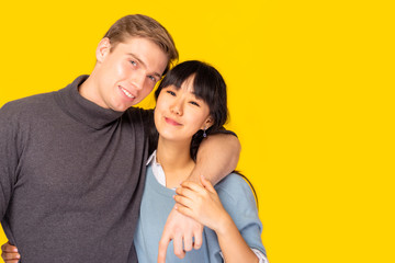 Portrait lovely fellow bonding soulmate or pretty young couple. in love each other. Boyfriend embracing asian girlfriend neck. Couple different nationality and age. copy space. yellow background