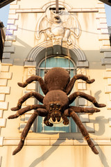 The brown spider doll climbs down from the building.