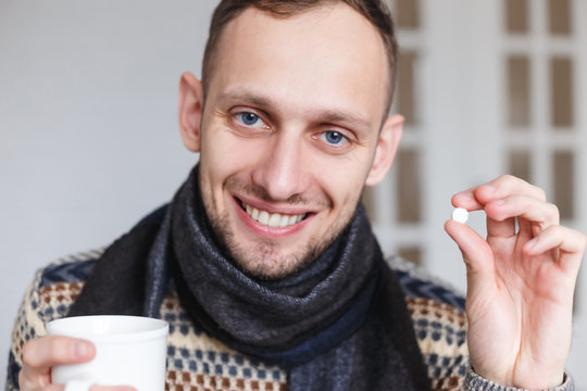 Smiling caught a cold man shows pills for health before taking