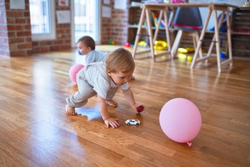Fototapeta premium Beautiful toddlers playing around lots of toys at kindergarten