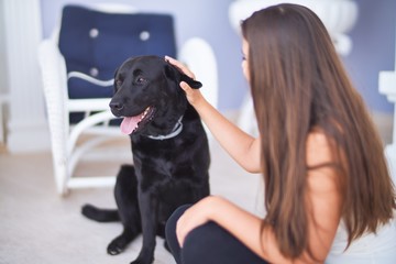 Young beautiful woman at terrace playing with black labrador dog