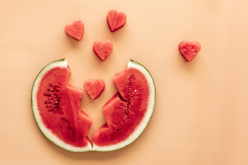 Fototapeta na wymiar Slice of watermelon and hearts on sandy background.