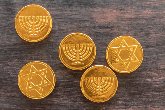 Chocolate coins with Jewish symbols on a wooden background.