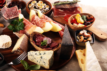 Italian antipasti wine snacks set. Cheese variety, Mediterranean olives, seafood salad, Prosciutto di Parma, tomatoes, anchovy and wine in glasses