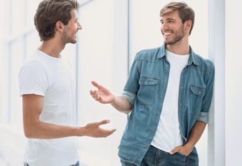two young employees are discussing something standing in the office corridor
