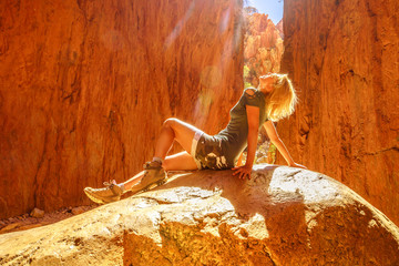 Lifestyle woman sunbathing sitting on a rock inside the canyon of Standley Chasm, an Aboriginal Land in West MacDonnell National Park. Australian outback Red Center, Northern Territory, Australia.