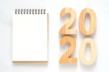 2020 wooden letters and blank notebook paper on white marble table background, 2020 new year mock...