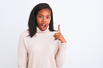 Beautiful young african american woman wearing turtleneck sweater over isolated background pointing finger up with successful idea. Exited and happy. Number one.