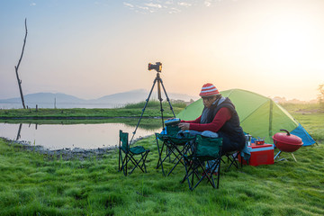 Naklejka premium Asian people come to camping and take pictures in the morning. Sun rise Asian river belt