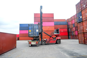 Container handlers put containers into work trucks in the harbor.