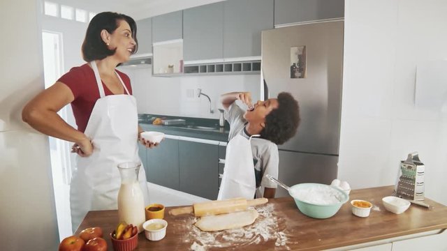 Young family cooking food in kitchen. Happy Little girl with her mother mixing batter. Mother and Little boy preparing the dough. Happy family in the kitchen and junior chef Concept. Cinematic 4k.