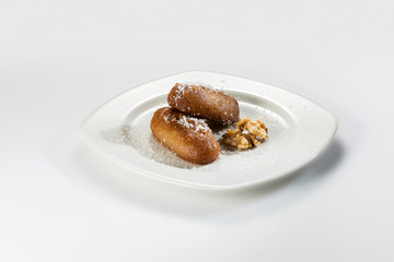 Riddled egg shaped sweet pastries in a white plate and on a white background.