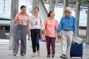 group of four happy asian Senior  tourists walking on street in urban city outdoors.  old man Travellers lifestyle  . elderly women vacation . ageing society concept. pensioner traveling . mature