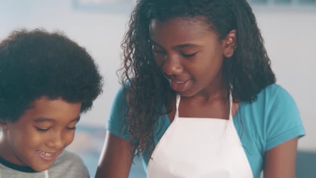 Young family cooking food in kitchen. Happy Little girl with her mother mixing batter. Mother and Little boy preparing the dough. Happy family in the kitchen and junior chef Concept. Cinematic 4k.