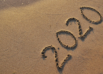 Symbols 2020 written on sand. 