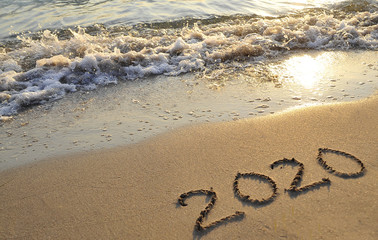 Symbols 2020 written on sand. 