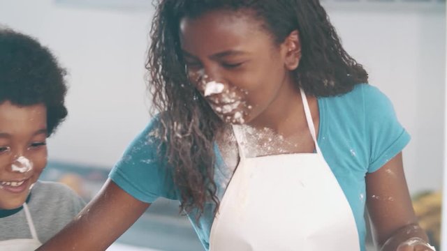 Young family cooking food in kitchen. Happy Little girl with her mother mixing batter. Mother and Little boy preparing the dough. Happy family in the kitchen and junior chef Concept. Cinematic 4k.