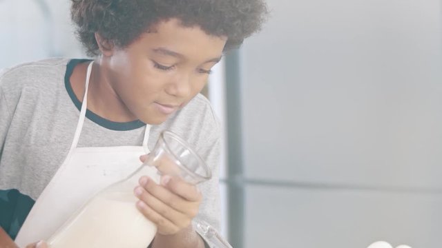 Young family cooking food in kitchen. Happy Little girl with her mother mixing batter. Mother and Little boy preparing the dough. Happy family in the kitchen and junior chef Concept. Cinematic 4k.